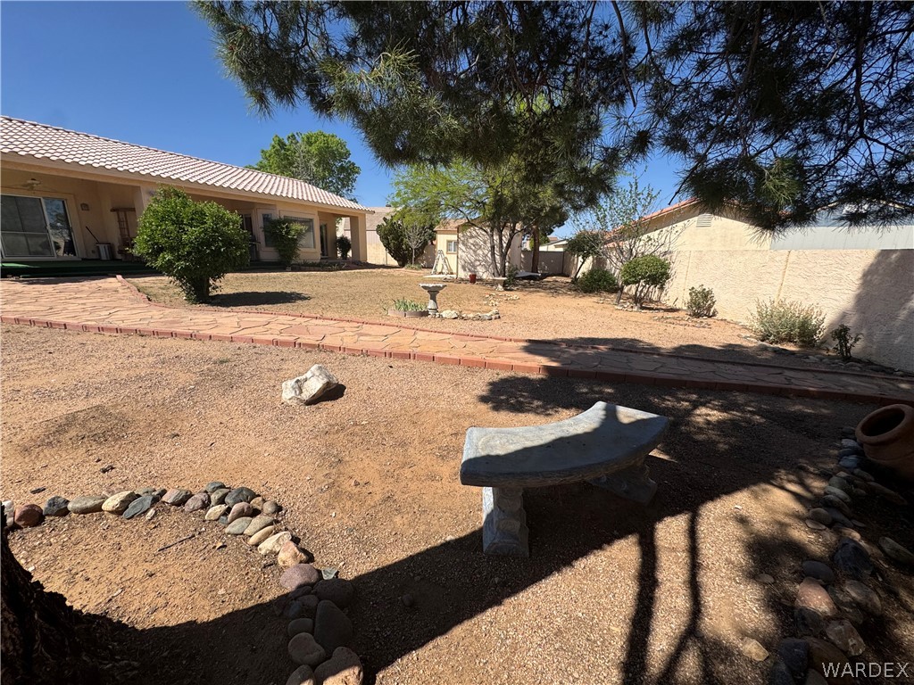 4029 Roma Road Kingman, AZ 86401 - Photo 59 of 90 The property features an extensive outdoor area with a flagstone and brick-lined pathway, mature trees, and a concrete bench