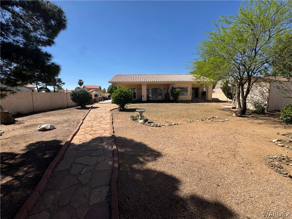 4029 Roma Road Kingman, AZ 86401 - Photo 60 of 90 The property features a stone pathway leading to the main residence, which has a tiled roof and glass doors along the rear