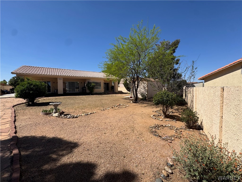4029 Roma Road Kingman, AZ 86401 - Photo 61 of 90 The property features a spacious backyard with a patio, covered porch, and a variety of mature trees and shrubs