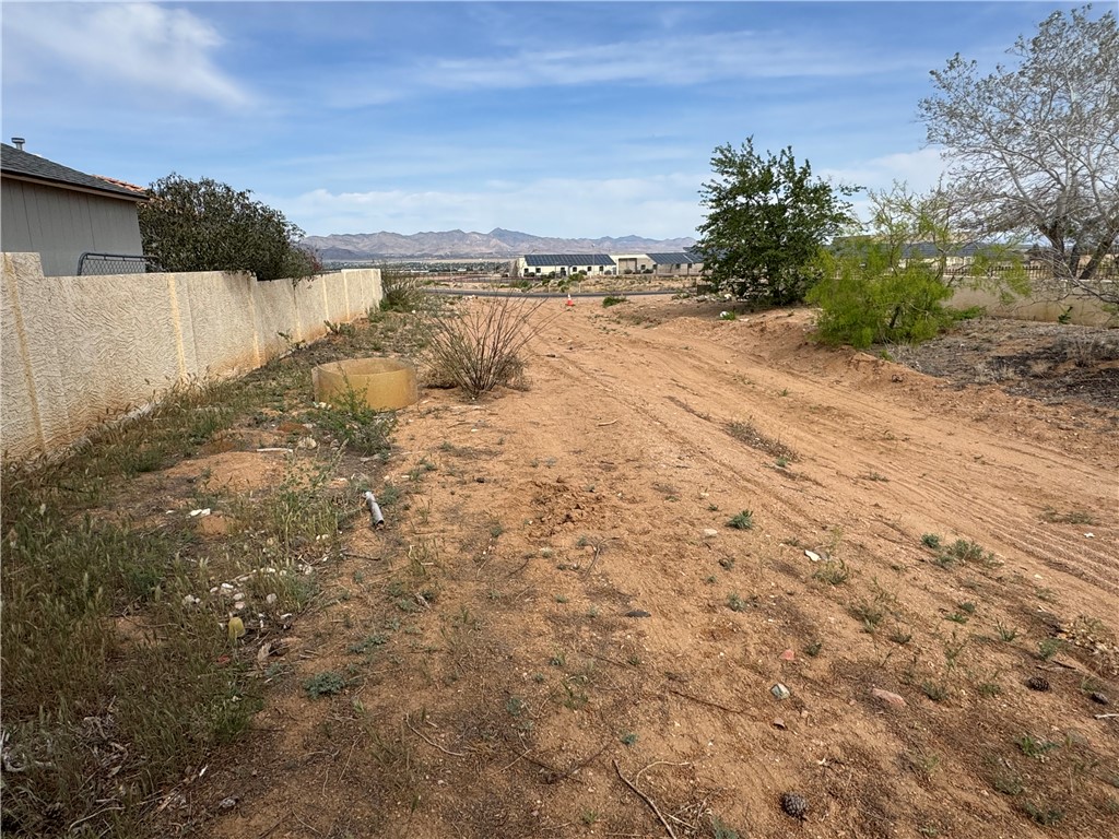 4029 Roma Road Kingman, AZ 86401 - Photo 63 of 90 The property offers a vast expanse of undeveloped land, featuring a textured privacy wall and a distant view of mountains under a partly cloudy sky