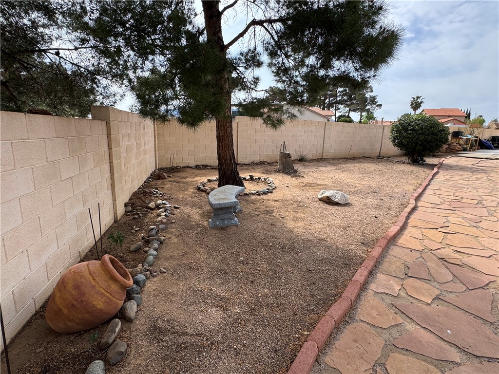 4029 Roma Road Kingman, AZ 86401 - Photo 66 of 90 The property features a spacious yard with a stone pathway, a mature tree, and a decorative stone bench