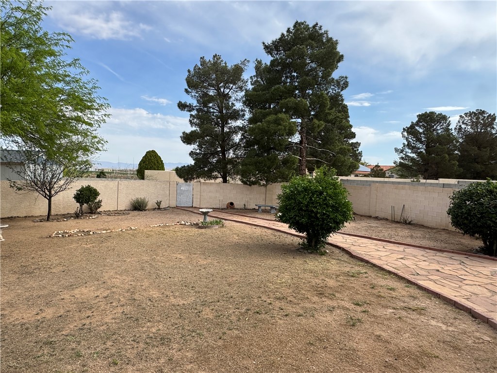 4029 Roma Road Kingman, AZ 86401 - Photo 77 of 90 The property features a spacious yard with a stone pathway, mature trees, and a block wall perimeter