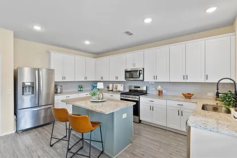 a kitchen with stainless steel appliances white cabinets a sink a stove a refrigerator and white cabinets