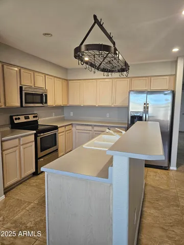 a kitchen with stainless steel appliances a stove a sink a microwave a refrigerator a stove and white cabinets