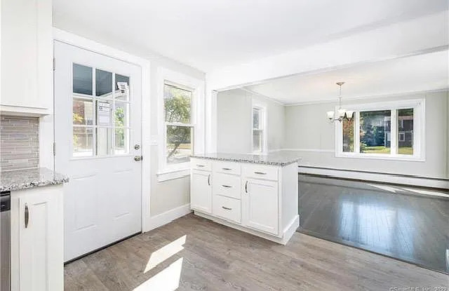 22 Fern Street Rocky Hill, CT 06067 - Photo 7 of 24 a large white kitchen with cabinets and wooden floor