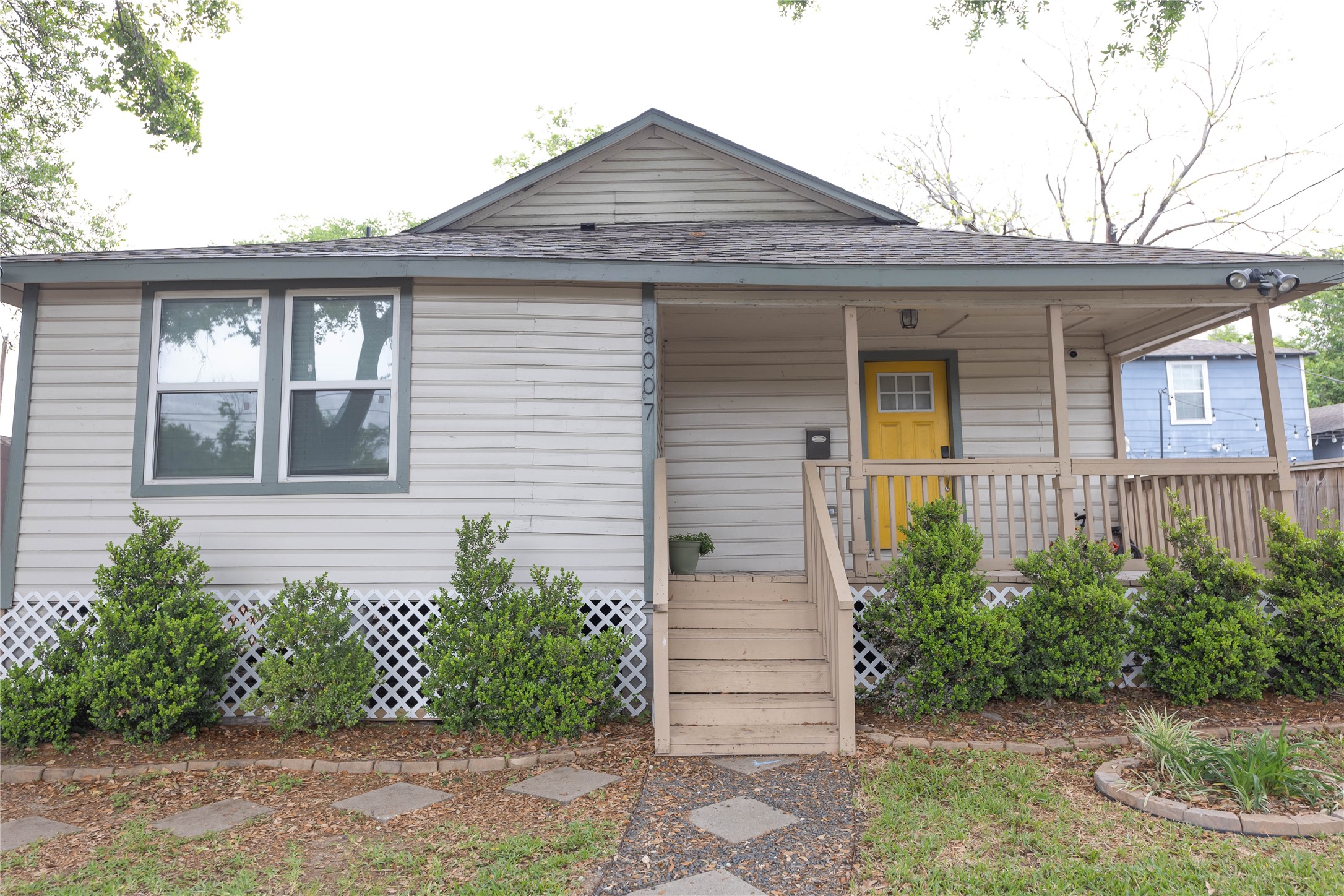 8007 Capitol Street Houston, TX 77012 - Photo 2 of 25 Charming single-story home with a welcoming front porch. Features a neat garden bordered by lush shrubs and a cozy wooden railing. Ideal for comfortable living with great curb appeal.