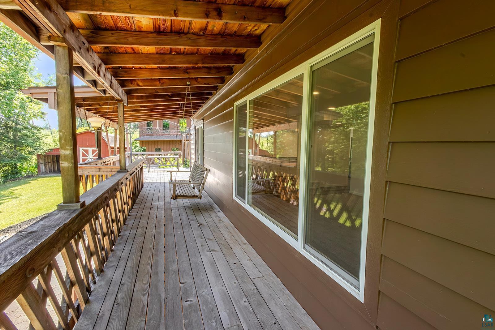 29 Ridge Road Esko, MN 55733 - Photo 36 of 41 Covered wood-plank porch with a natural wood ceiling, wood railing, and an adjacent exterior wall with horizontal siding