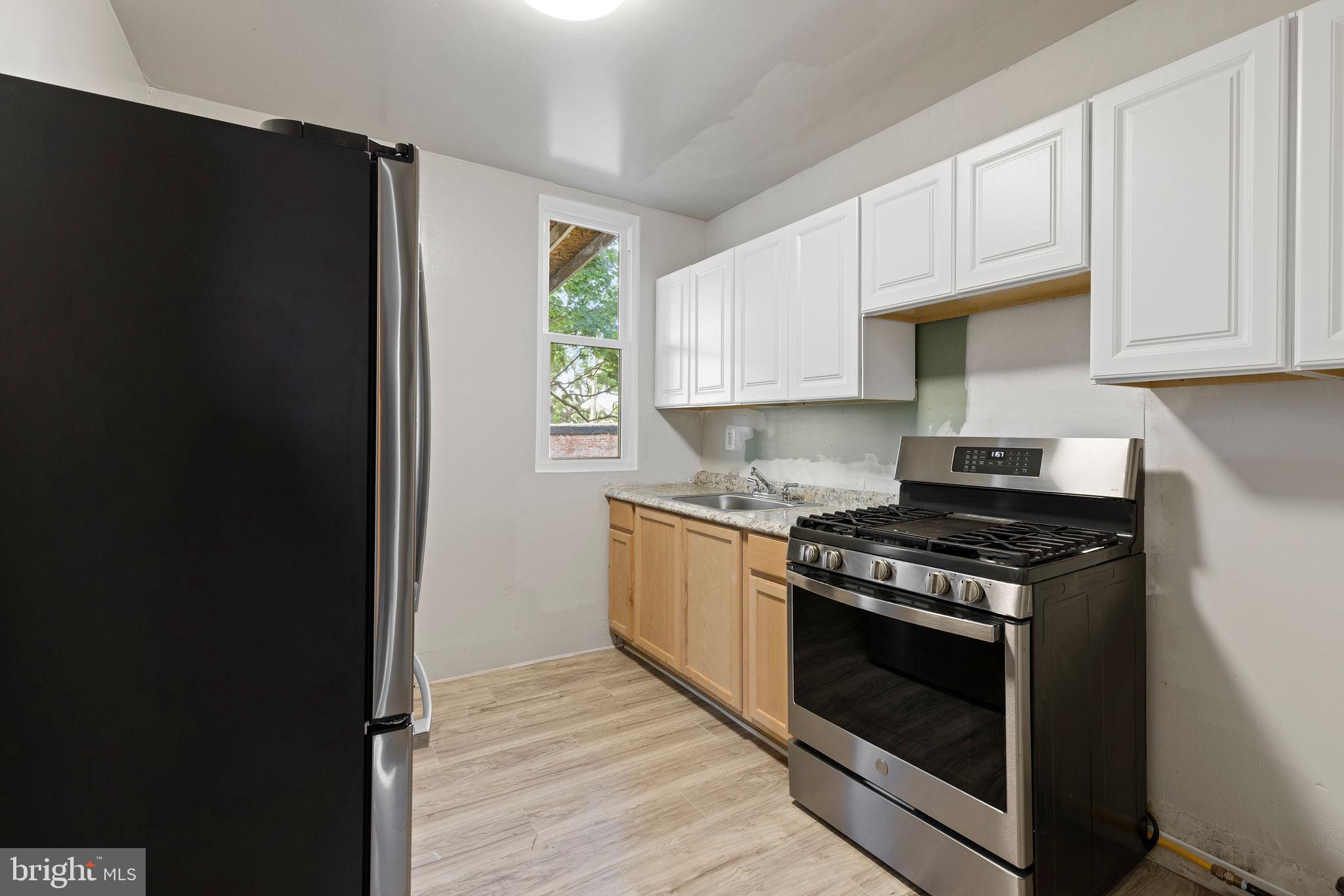 3003 Clifton Avenue Baltimore, MD 21216 - Photo 17 of 28 a kitchen with stainless steel appliances granite countertop white cabinets and a stove