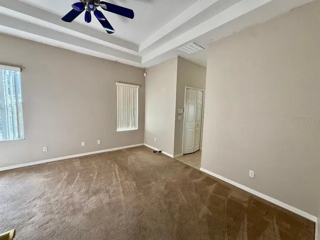 an empty room with ceiling fan and window