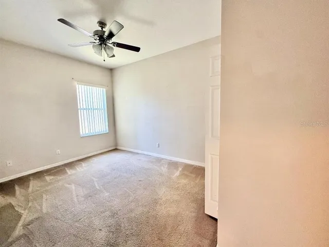 an empty room with a window and a chandelier fan