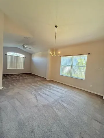 an empty room with windows and ceiling fan