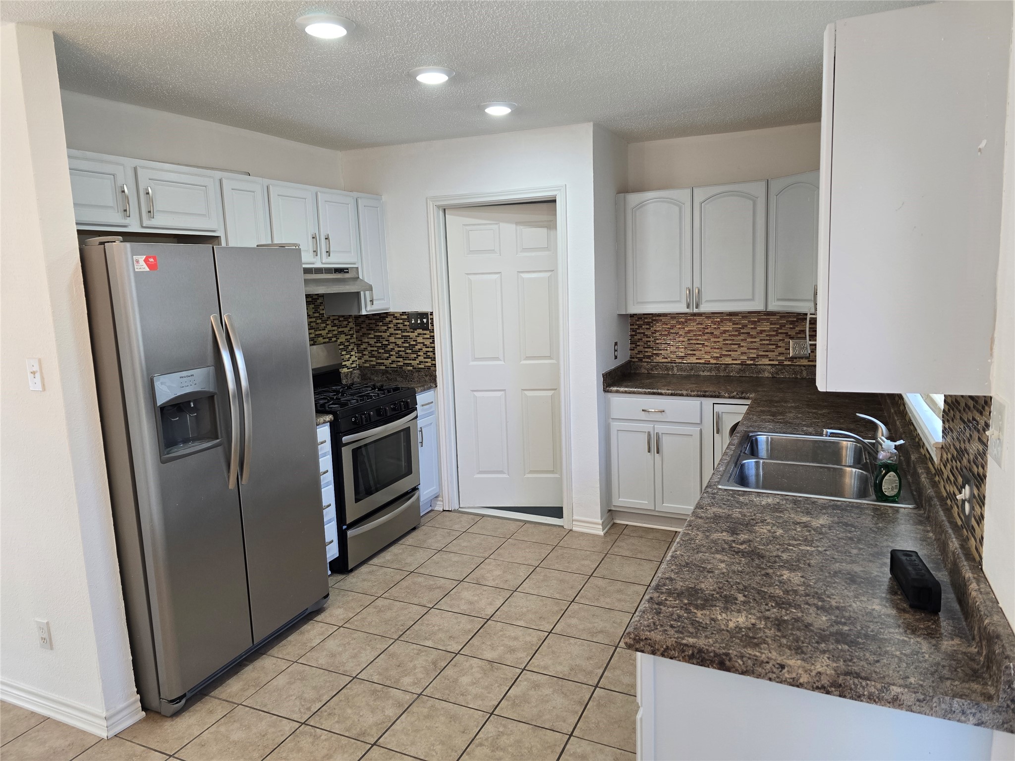 a kitchen with granite countertop a refrigerator and a sink