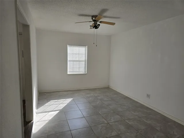 an empty room with a ceiling fan and windows