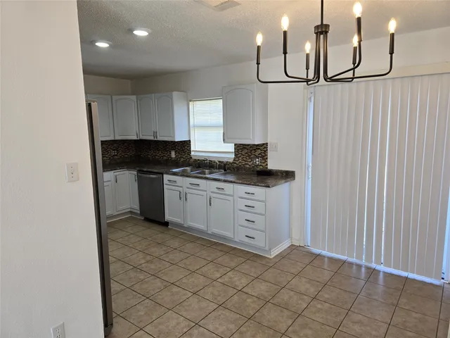 a kitchen with granite countertop a sink a stove and cabinets
