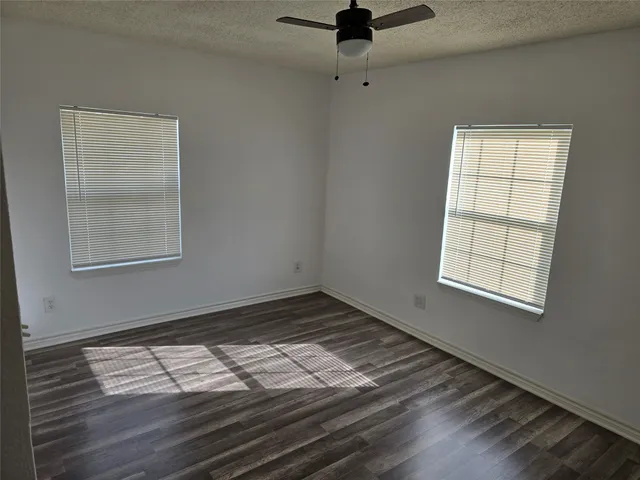 an empty room with wooden floor cabinet and windows