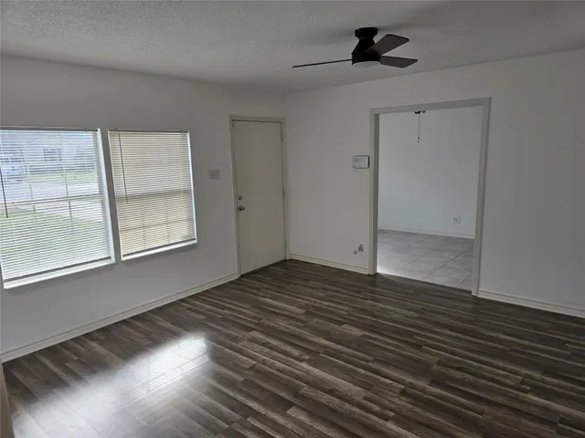 a view of an empty room with glass door and wooden floor