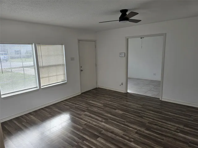 a view of an empty room with glass door and wooden floor