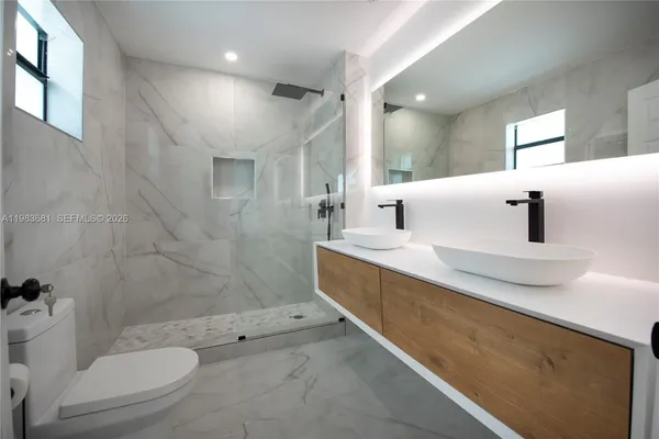 a bathroom with a double vanity sink toilet and shower