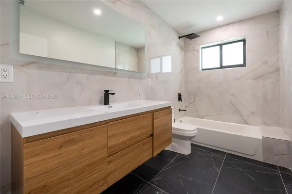 a bathroom with a tub sink toilet and a mirror