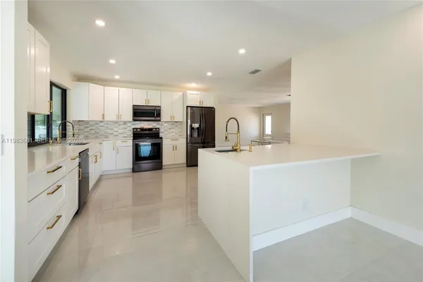 a large white kitchen with refrigerator a sink a stove and cabinets
