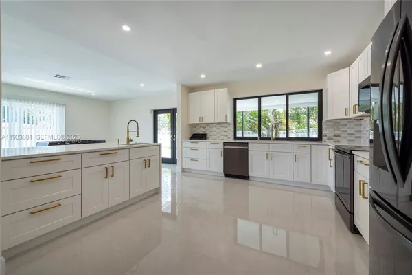 a large white kitchen with stainless steel appliances granite countertop a large counter top a stove and a refrigerator