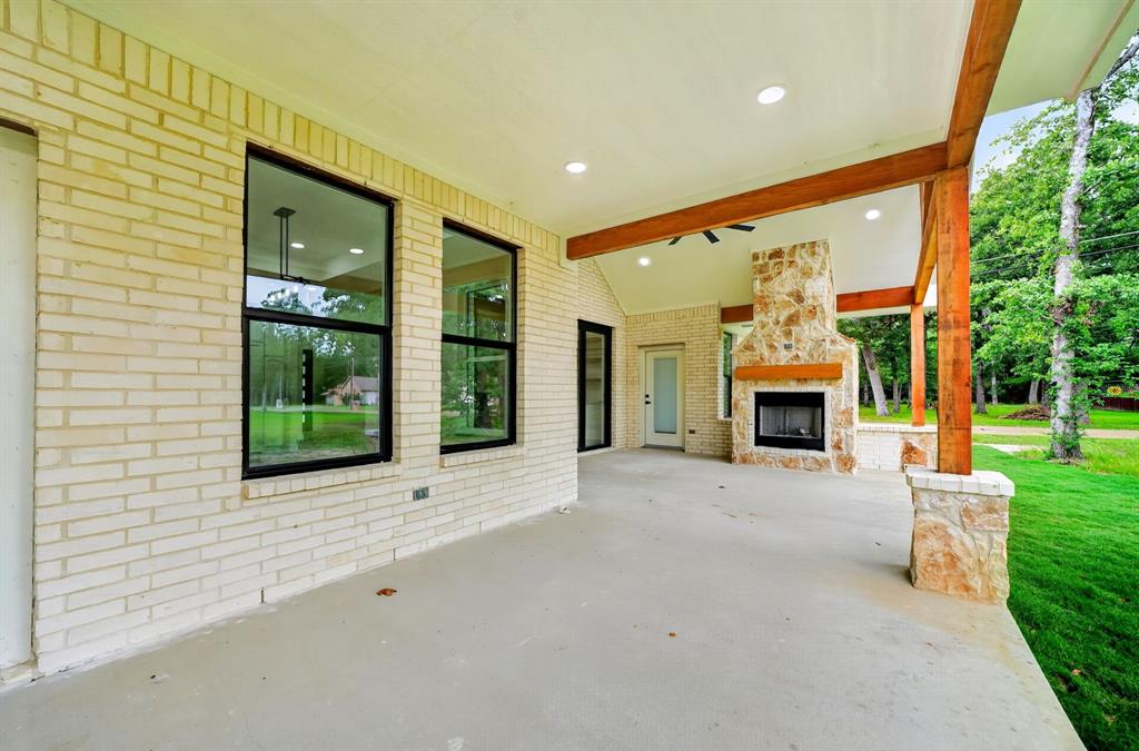 120 Springwood Road Enchanted Oaks, TX 75156 - Photo 34 of 37 Expansive covered patio featuring a stone fireplace with a wood-finish mantle, exposed wood beams, brick exterior, and recessed lighting