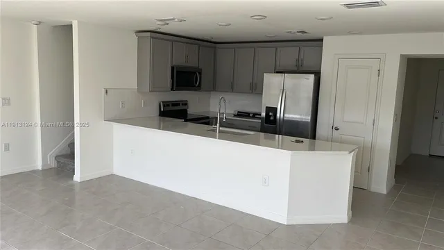 a kitchen with kitchen island a counter top space stainless steel appliances and cabinets
