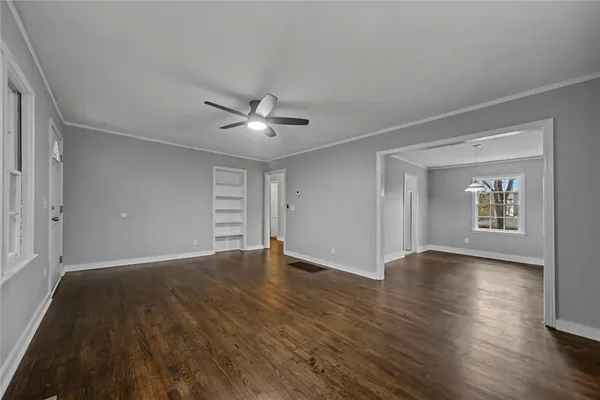 a view of an empty room with a window and wooden floor