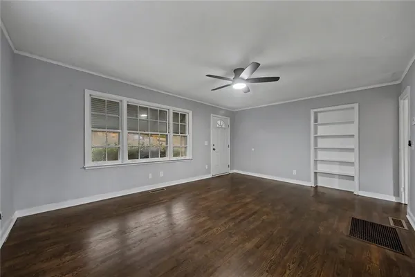 a view of an empty room with a window and wooden floor