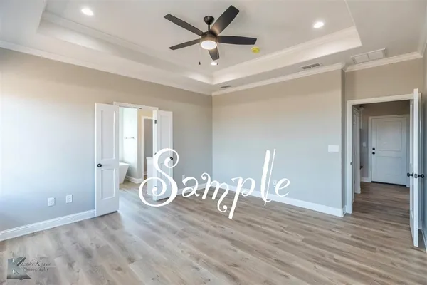 a view of an empty room with wooden floor and a ceiling fan