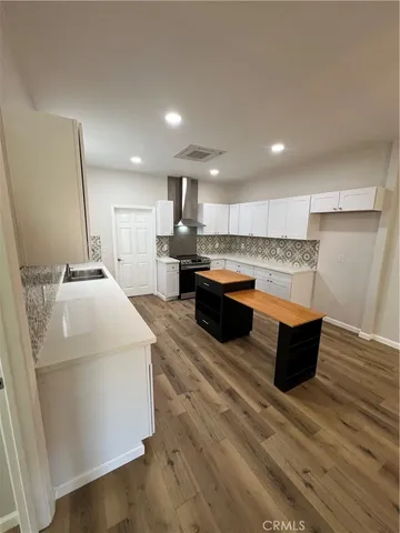 a large white kitchen with wooden floors and wooden cabinets