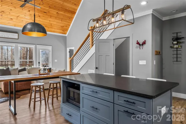 a kitchen with stainless steel appliances granite countertop a sink a stove and chairs with wooden floor