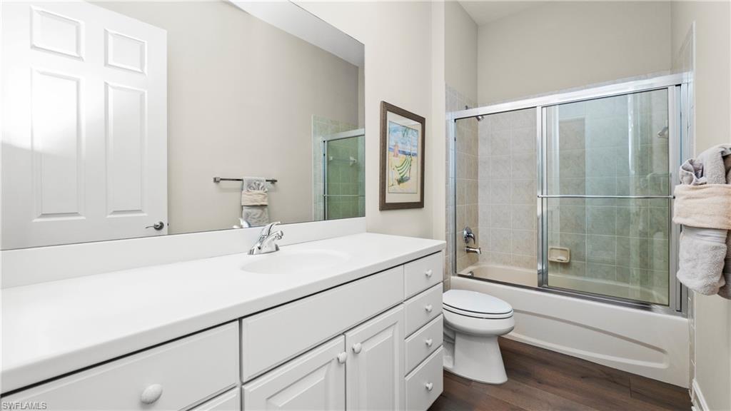 8617 Champions Point, Unit 403 Naples, FL 34113 - Photo 29 of 37 Full bathroom with vanity, dark wood finished floors, and enclosed tub / shower combo