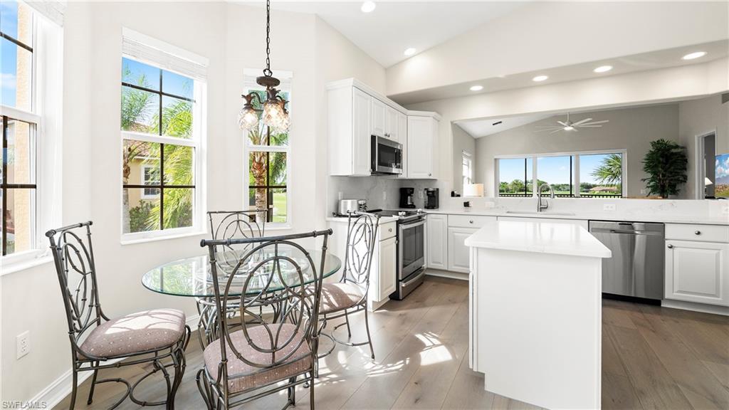 8617 Champions Point, Unit 403 Naples, FL 34113 - Photo 6 of 37 Kitchen with lofted ceiling, white cabinetry, a kitchen island, appliances with stainless steel finishes, and light wood-style floors