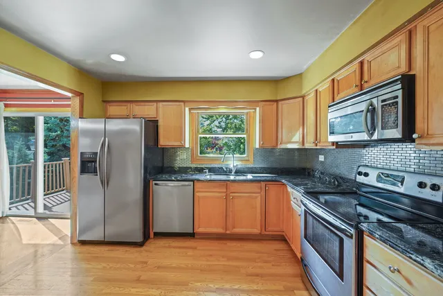 a kitchen with stainless steel appliances granite countertop a refrigerator a stove a sink and a microwave