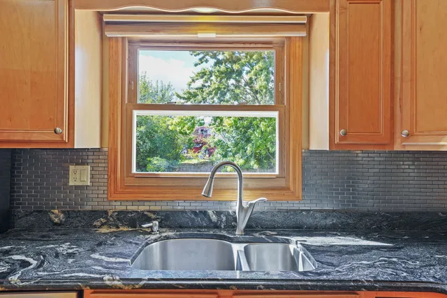 a kitchen sink with a granite countertop window and sink