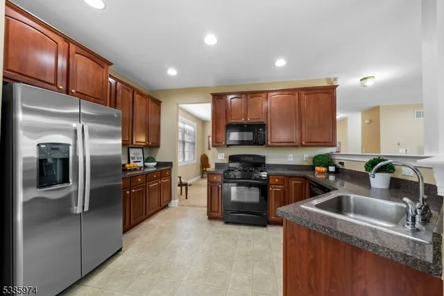 a kitchen with stainless steel appliances granite countertop a refrigerator a sink a stove a oven with wooden cabinets