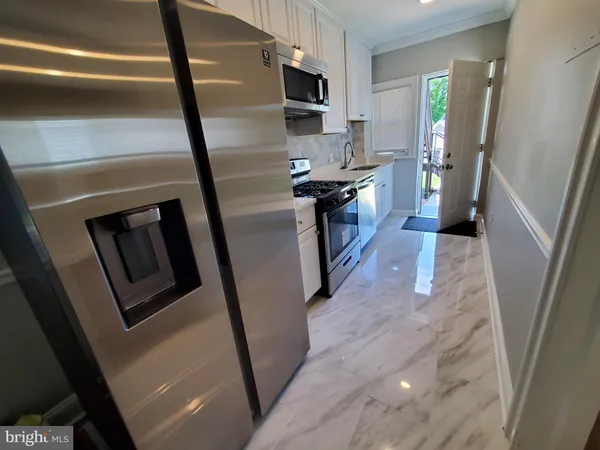 a view of a kitchen with fridge and wooden floor