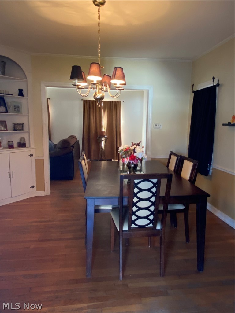 Dining room with ornamental molding, hardwood flooring, and an inviting chandelier and built-in cabinet