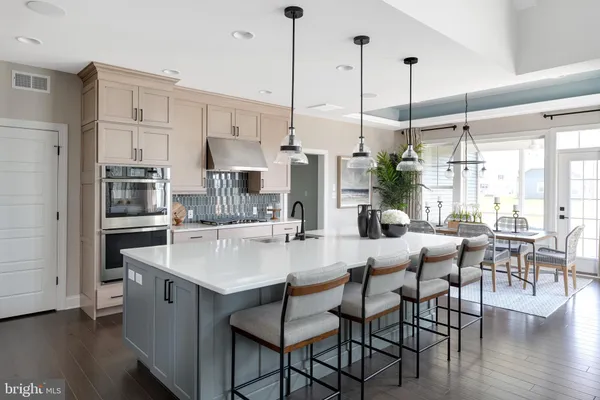 a kitchen with stainless steel appliances kitchen island granite countertop a dining table chairs and a refrigerator