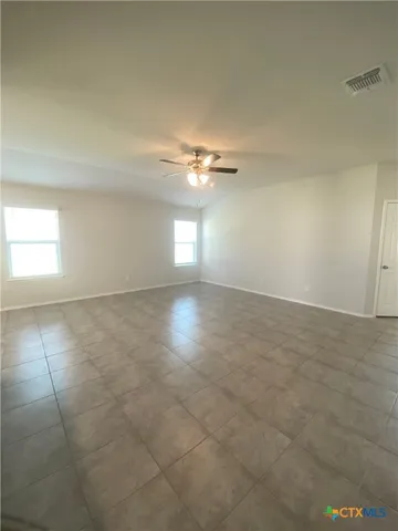 an empty room with a ceiling fan and window