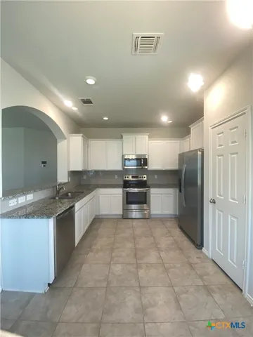 a kitchen with granite countertop a refrigerator and a stove top oven