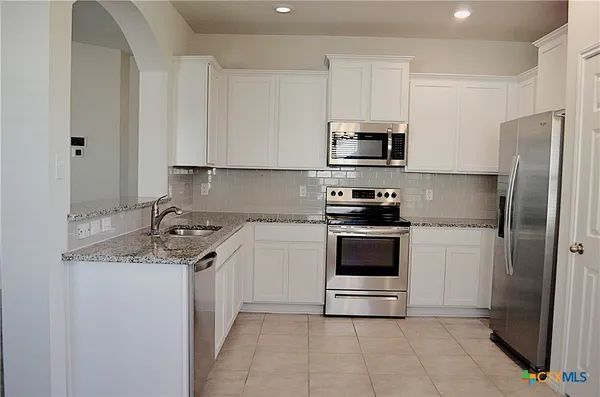 a kitchen with granite countertop a sink and white cabinets