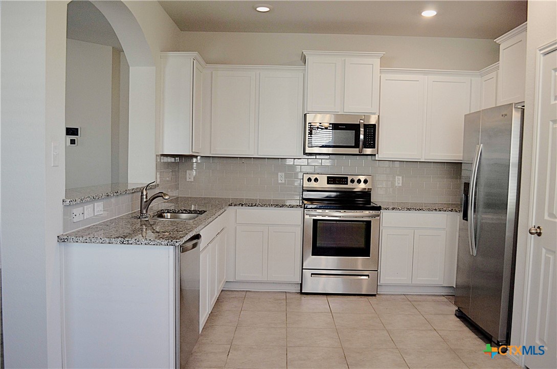 2606 Cortona Street Harker Heights, TX 76548 - Photo 9 of 40 a kitchen with stainless steel appliances granite countertop a refrigerator stove and white cabinets