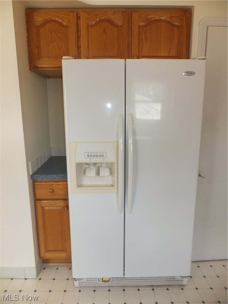 7701 Spring Garden Road Cleveland, OH 44129 - Photo 6 of 27 Kitchen featuring white refrigerator with ice dispenser, brown cabinets, and light tile floors