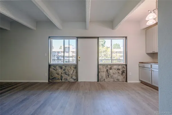 an empty room with wooden floor and windows