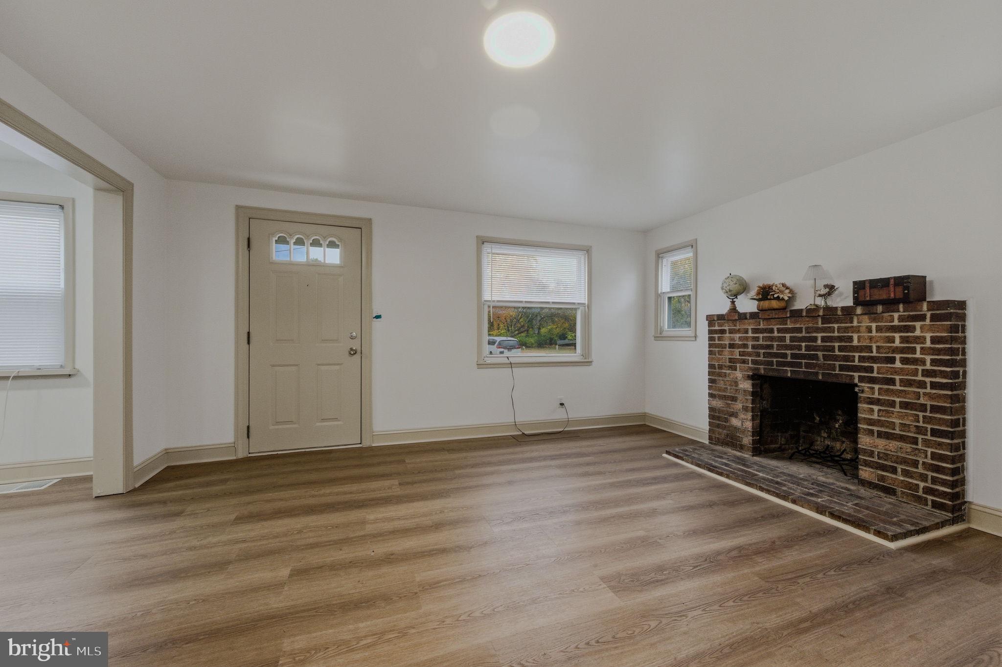 208 Harding Avenue Wilmington, DE 19804 - Photo 5 of 28 an empty room with wooden floor fireplace and windows