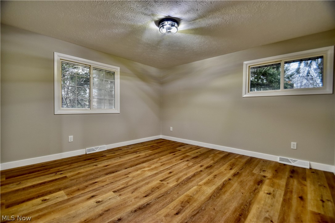 7520 Johnnycake Ridge Road Mentor, OH 44060 - Photo 31 of 36 Empty room featuring a textured ceiling, hardwood / wood-style floors, and plenty of natural light