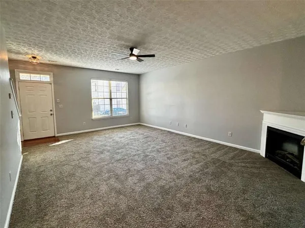an empty room with windows and fireplace
