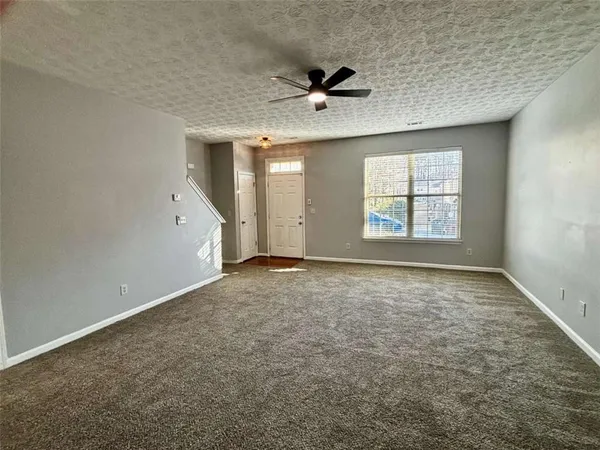 an empty room with a ceiling fan and window